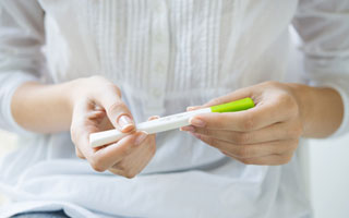 Нужно пройти тест на беременность Женщина держит в руках тест на беременность